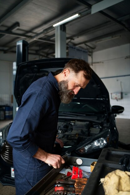Mecánico masculino que trabaja en un taller de reparación de automóviles en un automóvil