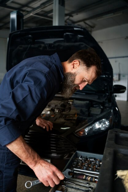 Mecánico masculino que trabaja en un taller de reparación de automóviles en un automóvil