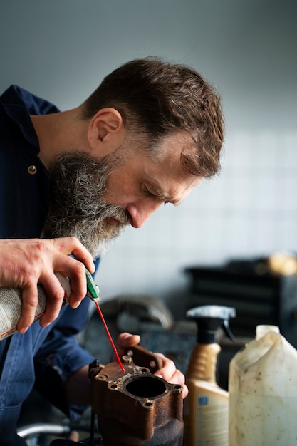 Mecánico masculino que trabaja en un taller de reparación de automóviles en un automóvil