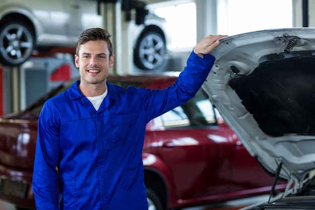 Foto gratuita mecánico que se coloca cerca del coche en taller de reparaciones