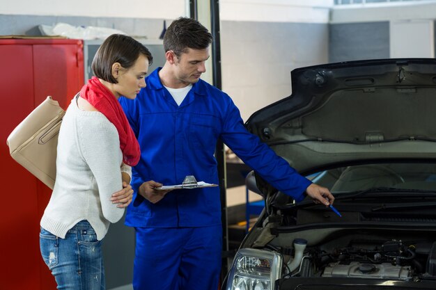 Mecánico que muestra al cliente el problema con el coche