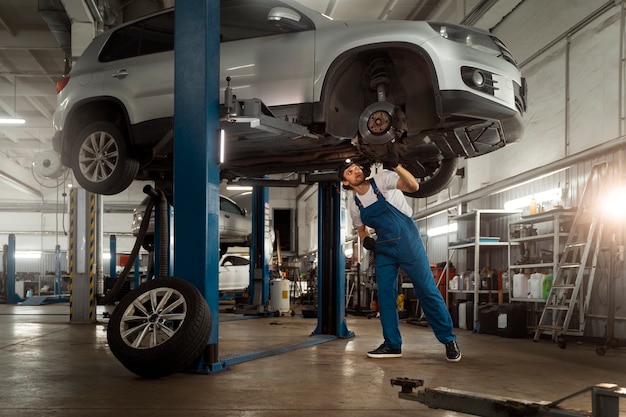 Foto gratuita mecánico que trabaja en la suspensión del automóvil en el taller de reparación