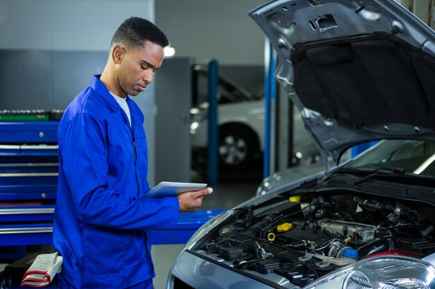 Mecánico que usa la tabla digital, mientras que el examen de los coches