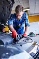 Foto gratuita mecánico reparando un coche en el taller.