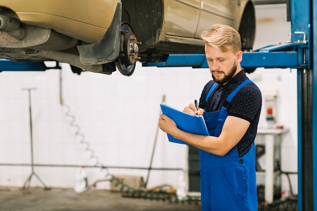 Foto gratuita mecánico revisando el automóvil en el taller