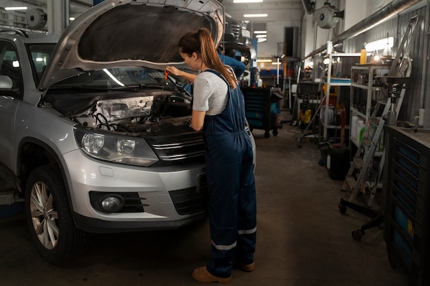 Foto gratuita mecánico de sexo femenino que trabaja en la tienda en un coche