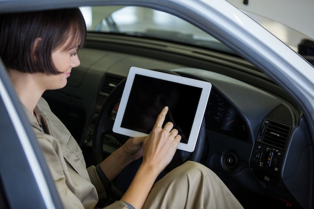 Foto gratuita mecánico de sexo femenino que usa la tableta digital en coche
