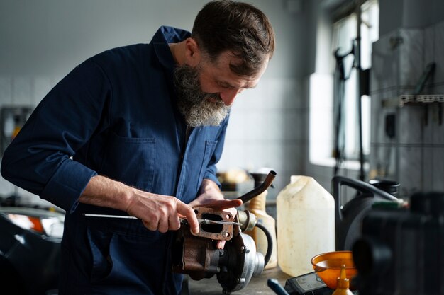 Mecánico de sexo masculino que trabaja en el coche en el taller de reparación de automóviles