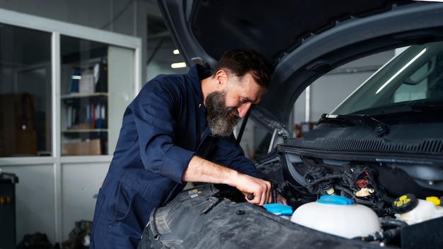 Mecánico de sexo masculino que trabaja en el coche en el taller de reparación de automóviles