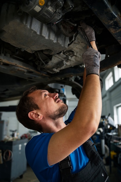 Mecánico de sexo masculino que trabaja en el coche en el taller de reparación de automóviles