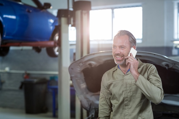 Foto gratuita mecánico sonriente hablando por un teléfono móvil