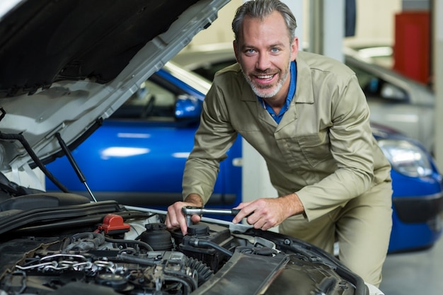 Mecánico sonriente durante el servicio de un motor de automóvil