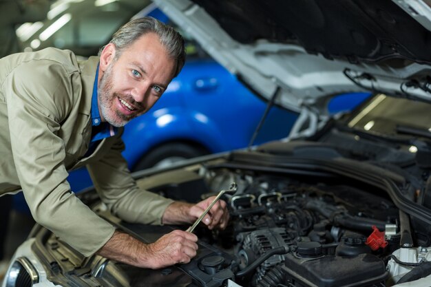 Mecánico sonriente durante el servicio de un motor de automóvil