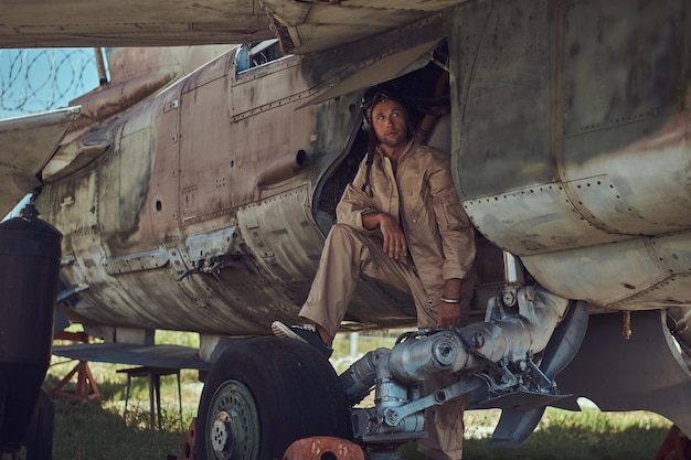 El mecánico con uniforme y casco de vuelo realiza el mantenimiento de un antiguo bombardero militar en el museo al aire libre.