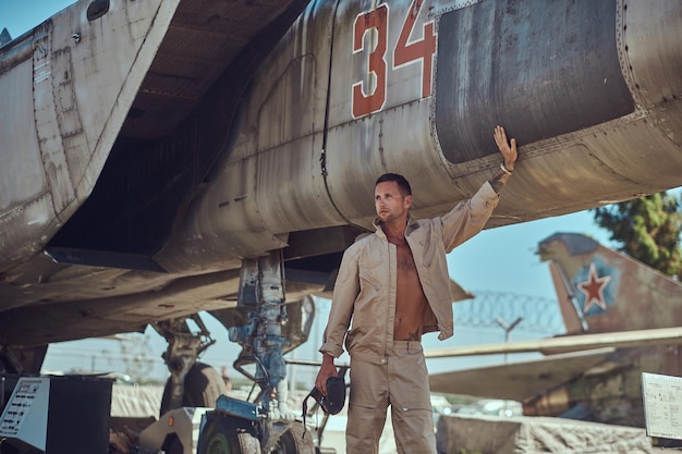 Mecánico en uniforme de pie cerca de un interceptor de combate de guerra en un museo al aire libre.