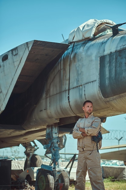 Mecánico en uniforme de pie cerca de un interceptor de combate de guerra en un museo al aire libre.