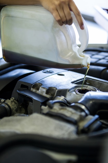 Mecánico verter lubricante de aceite en el motor de un coche