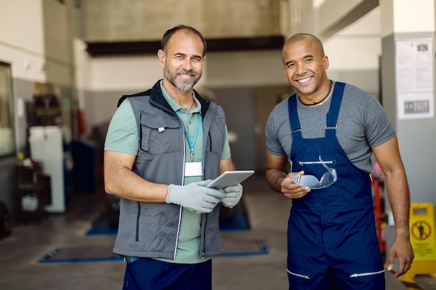 Mecánicos de automóviles felices trabajando juntos en un taller