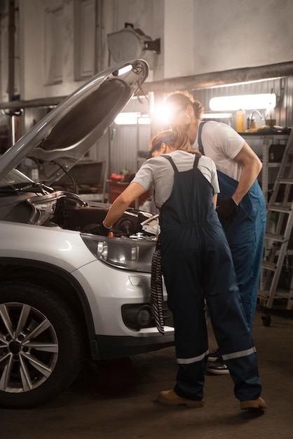 Mecánicos masculinos y femeninos que trabajan en la tienda de un automóvil