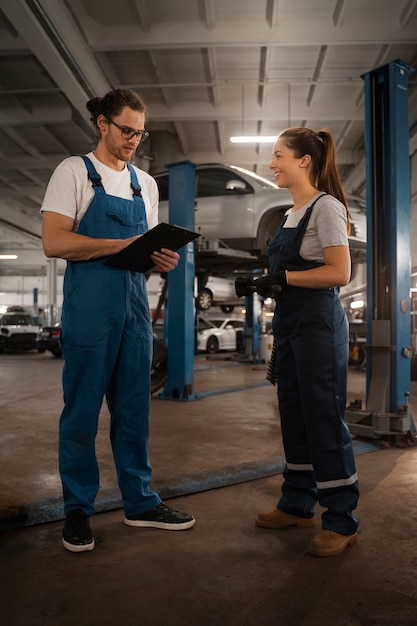 Foto gratuita mecánicos masculinos y femeninos que trabajan en la tienda de un automóvil