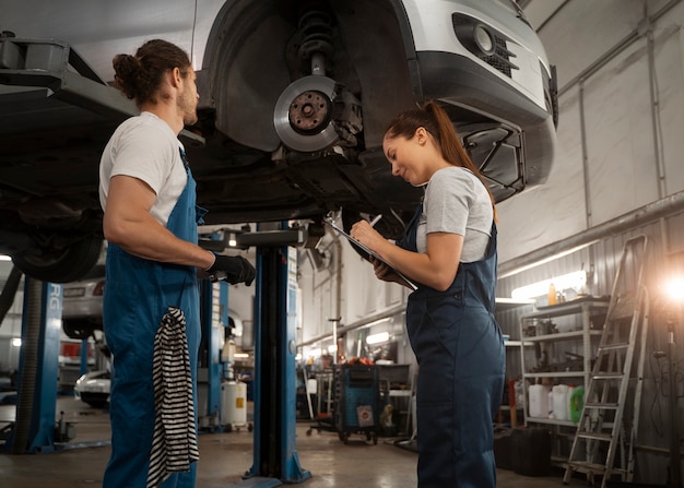 Foto gratuita mecánicos masculinos y femeninos que trabajan en la tienda de un automóvil