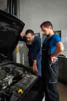 Foto gratuita mecánicos masculinos trabajando juntos en el coche en la tienda