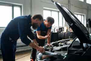 Foto gratuita mecánicos masculinos trabajando juntos en el coche en la tienda