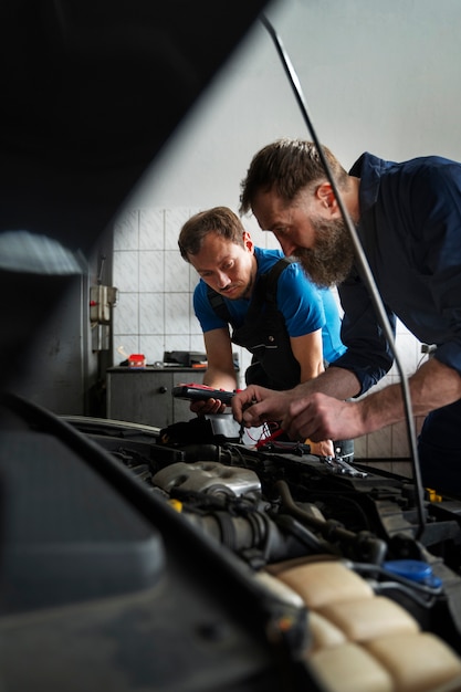 Foto gratuita mecánicos masculinos trabajando juntos en el coche en la tienda