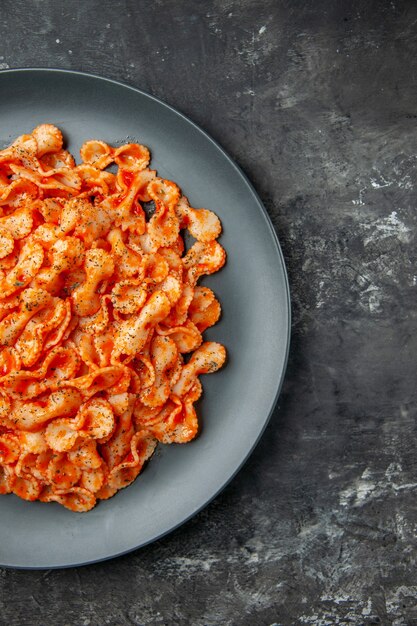 Media foto de deliciosa pasta en un plato negro para cenar en el lado derecho sobre fondo oscuro