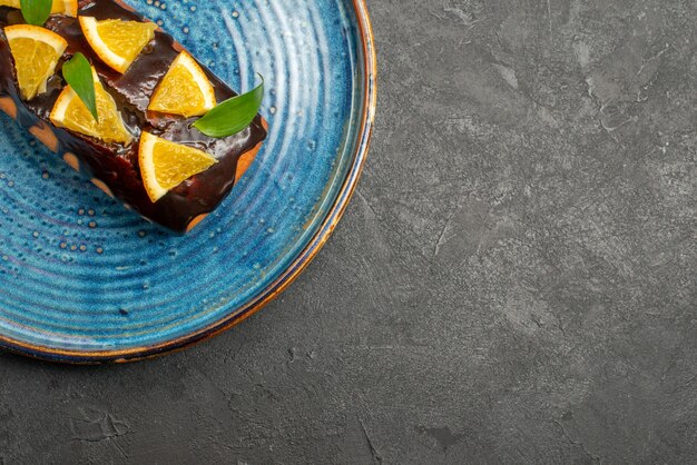 Media foto de pastel suave decorado con naranja y chocolate sobre mesa oscura