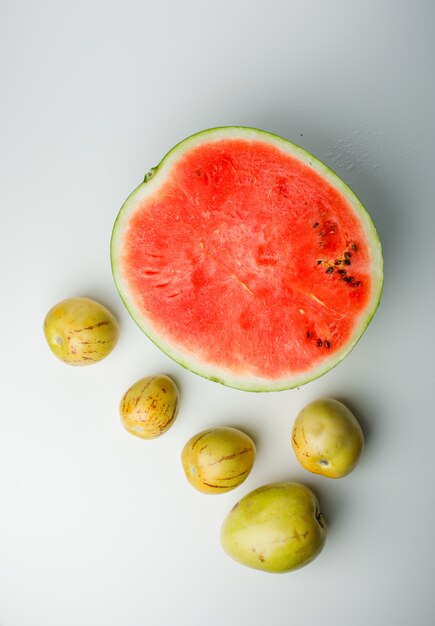 Media sandía con manzanas maduras sobre fondo blanco degradado