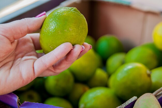 Mediados de la sección de la mujer que compra la cal dulce en el supermercado. Mujer que compra las frutas en mercado verde orgánico. Mujer, elegir, fresco, cal