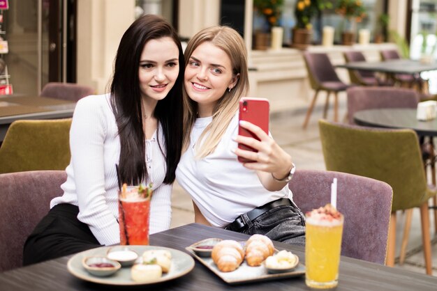 Medianas mujeres que toman un selfie en el restaurante.