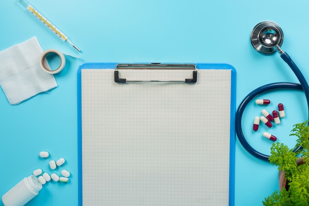 Foto gratuita de medicamentos, suministros médicos colocados junto a tableros de escritura y herramientas médicas en un azul.