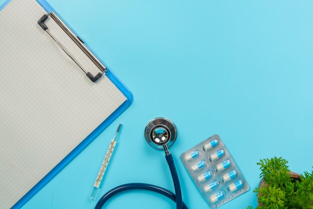 de medicamentos, suministros médicos colocados junto a tableros de escritura y herramientas médicas en un azul.