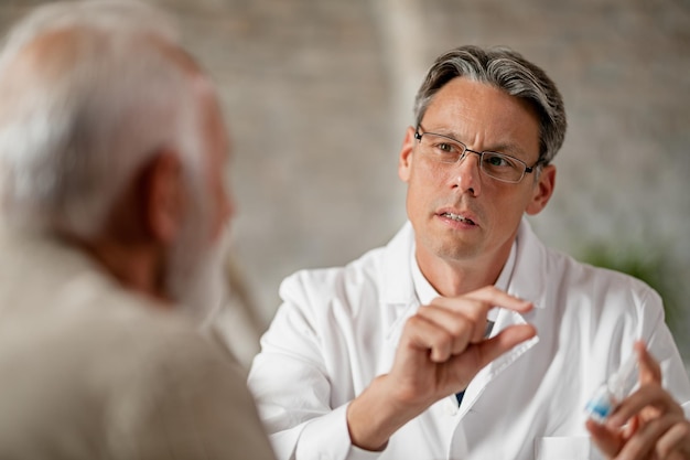 Médico adulto medio que tiene consultas con pacientes mayores sobre medicamentos recetados en la clínica