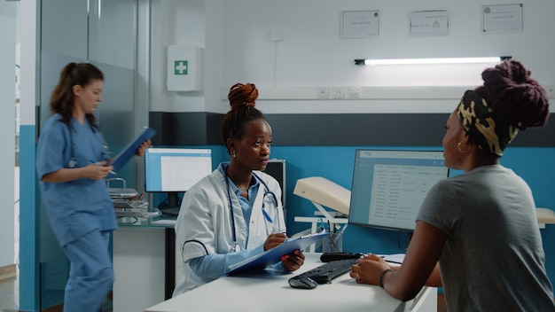 Médico afroamericano y paciente haciendo consulta