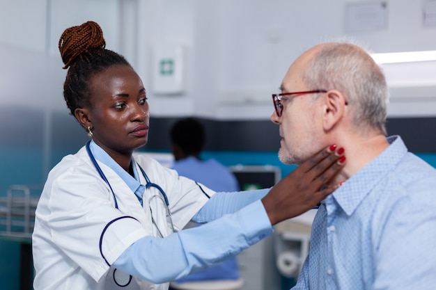 Médico afroamericano revisando paciente senior