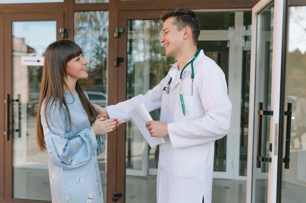 Médico alegre y paciente en la entrada de la clínica