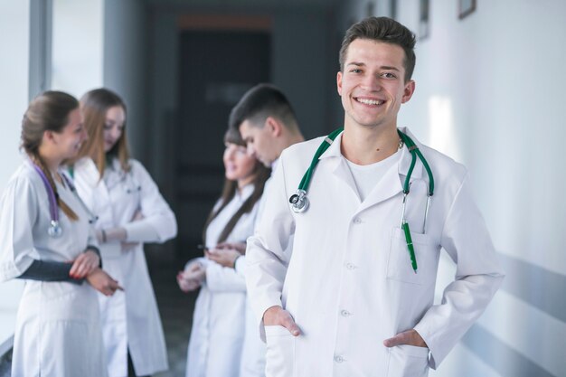 Médico alegre de pie con colegas en el fondo