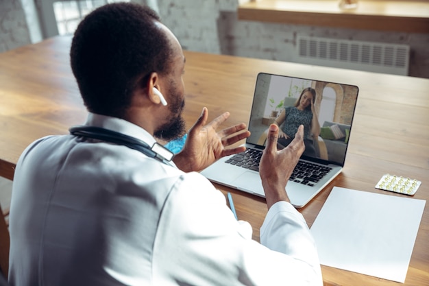 Médico asesorando al paciente en línea con una computadora portátil