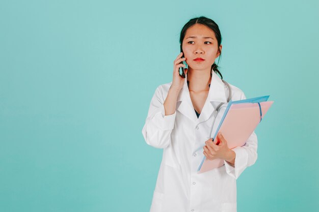 Médico asiático serio hablando en el teléfono