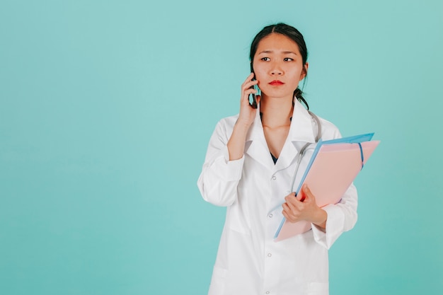 Médico asiático serio hablando en el teléfono