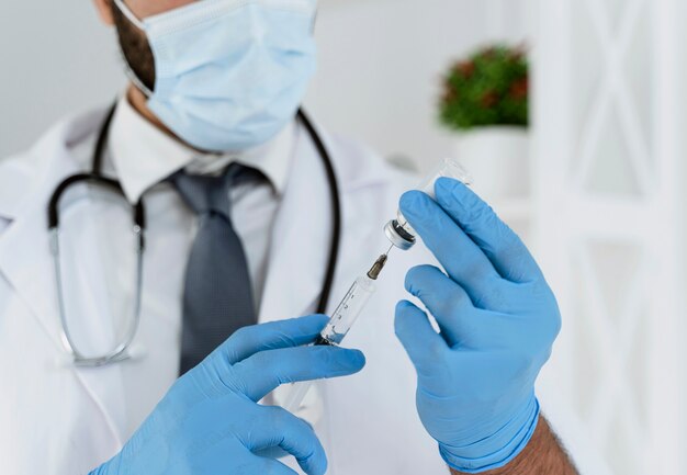Médico borrosa con máscara médica sosteniendo una jeringa