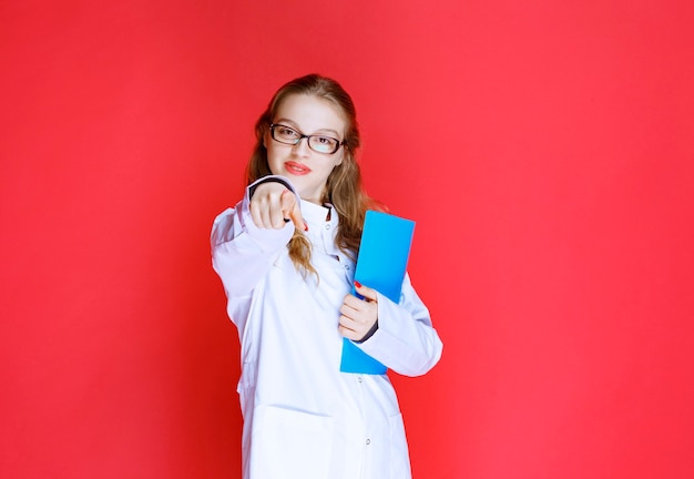 Médico con una carpeta azul saludando a su paciente.