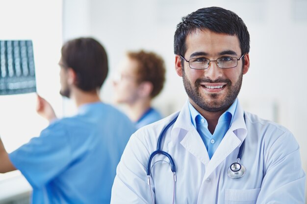 Médico con compañeros de trabajo de fondo