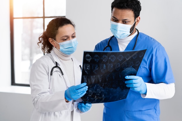 Médico y enfermera de tiro medio mirando una radiografía.