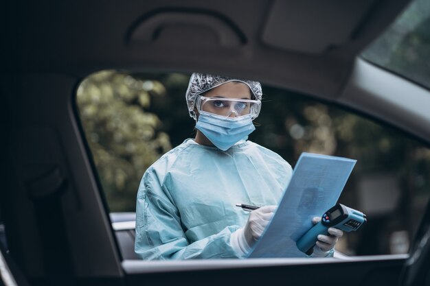 Médico epidemiólogo luchando contra el coronavirus COVID-19. La enfermera usa un traje protector y una máscara durante el brote de COVID19.