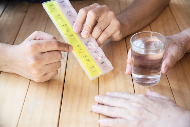 El médico es ayudar al paciente a comer la tableta de medicina en el pastillero correctamente