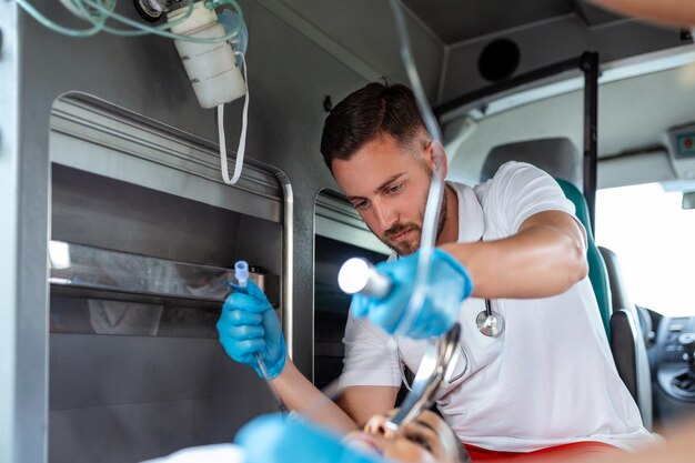 El médico está listo para la intubación endotraqueal para un paciente que no respira Una joven paramédica sostiene una solución iv Los paramédicos de EMS brindan ayuda médica a un paciente lesionado camino a un hospital